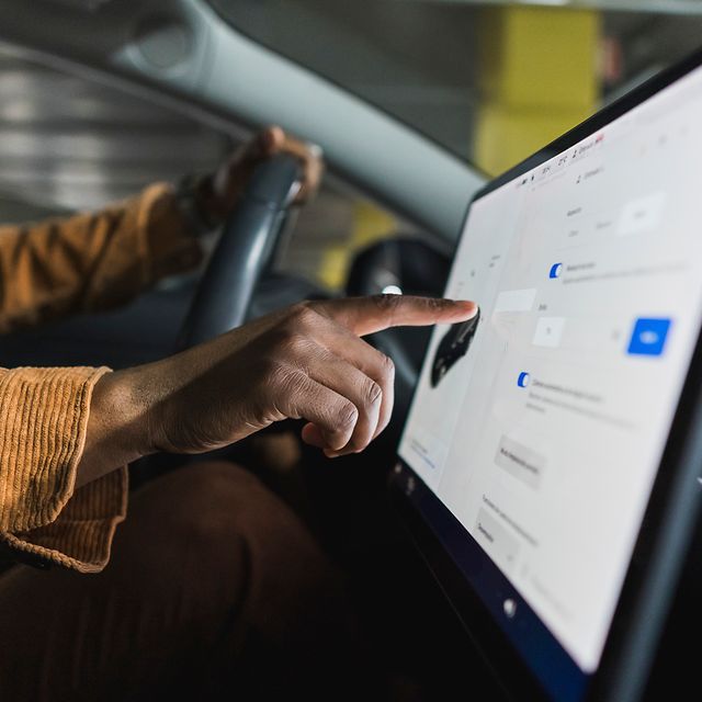 Eine Hand bedient einen Auto-Touchscreen, der mit HotSpot Drive während der Fahrt online ist.