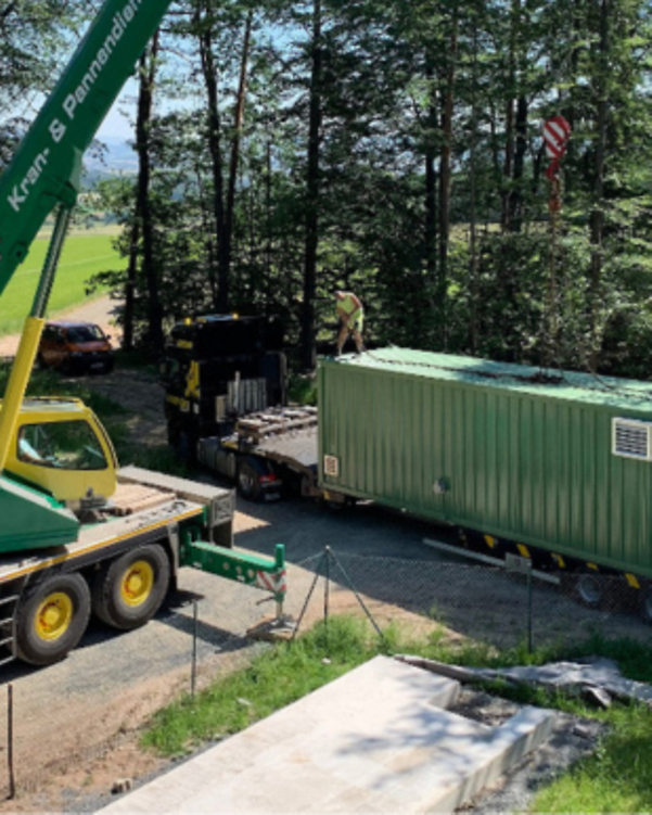 Kran hebt Wasseraufbereitungs-Container von LKW