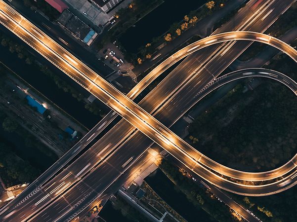 Luftaufnahme eines beleuchteten Autobahnkreuzes.