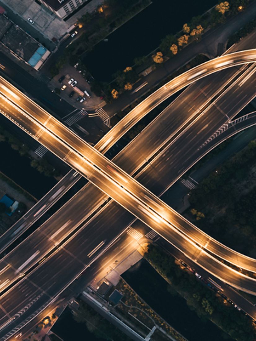 Luftaufnahme eines beleuchteten Autobahnkreuzes.