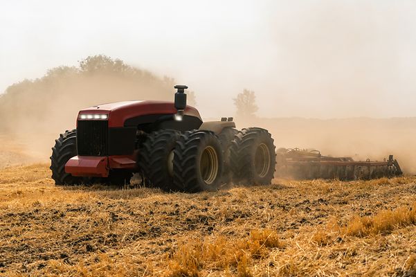 Moderner Traktor pflügt ein staubiges Feld.