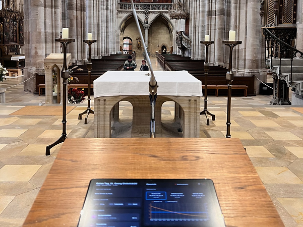 Kirchenraum mit Altar, Mikrofon und digitalem Bedienpanel im Vordergrund.
