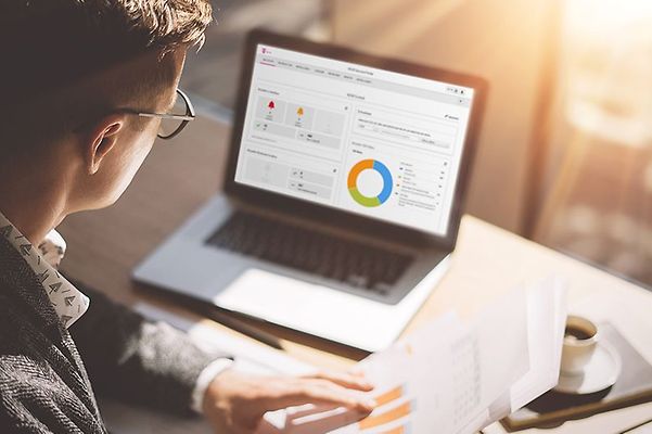 Mann arbeitet am Laptop mit IoT-Kundenportal und Diagrammen auf dem Bildschirm.