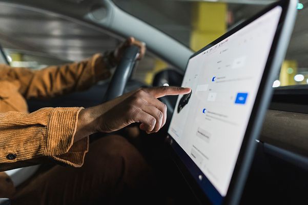 Person in a car tapping on a touchscreen.