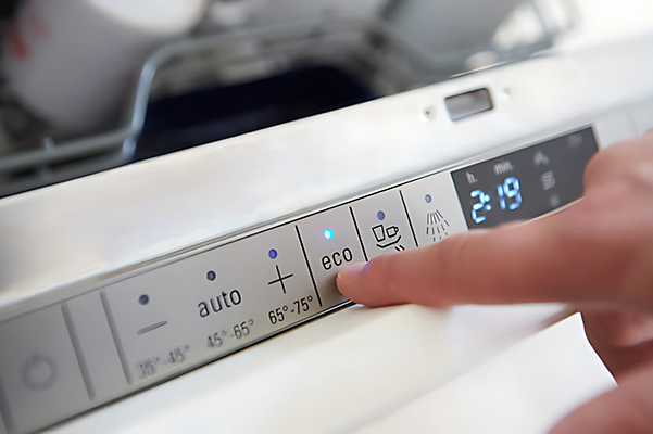 Finger tapping the eco mode on a dishwasher to save energy.