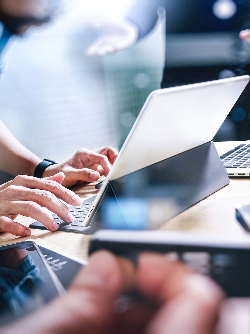 Person touching a laptop and tablet on a table with an abstract network overlay.