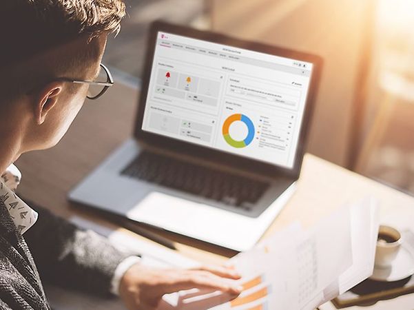 A person views a data analysis with charts for the IoT M2M Service Portal on a laptop.