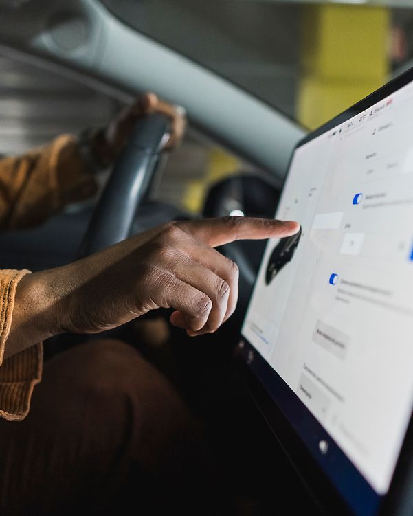 Driver operating the touchscreen of a modern connected vehicle.