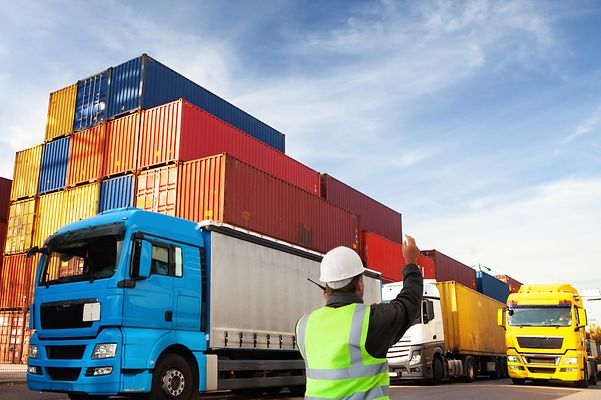 An employee coordinates trucks at the cargo port with a radio.
