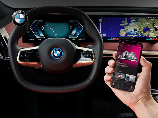 View of a BMW car dashboard with smartphone showing Telekom MagentaTV app.